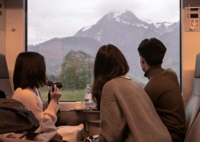 three people sitting on a train looking out the window