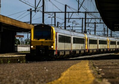 a yellow and white train traveling past a train station