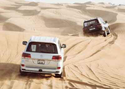 two cars driving in the sand in the desert