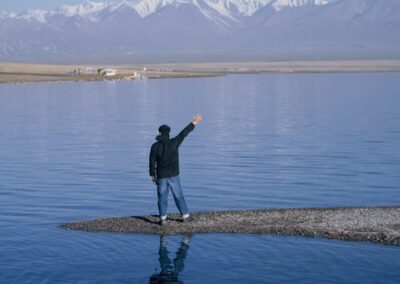Person waving on a small land strip in a lake.