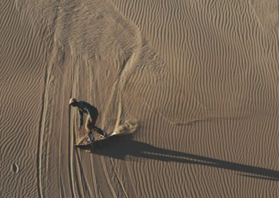 person in black shirt walking on brown sand