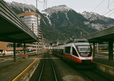 Modern train at a station with mountains behind.