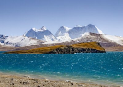 Turquoise lake with snowy mountains and island.